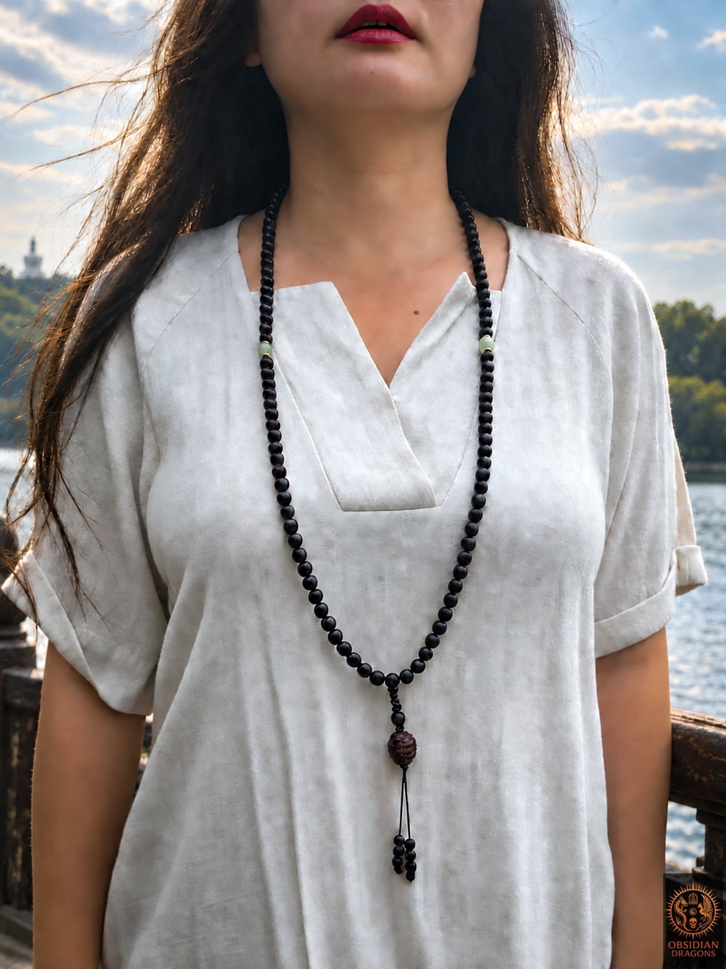 Vue frontale d’une femme portant le mala de prière de 108 perles en santal rouge et jade néphrite, avec carapace de tortue