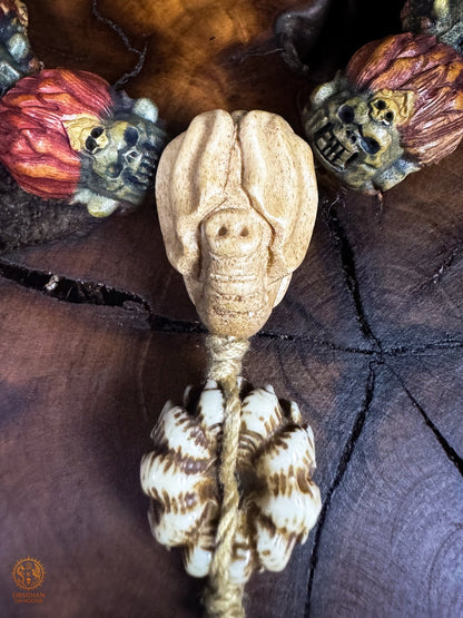 Gros plan du revers de la perle Guru Ganesh Kangiten en bois de cerf, encadrée par deux têtes de Mahakala polychromes