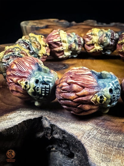 Revers des perles Mahakala en bois de cerf montrant les chevelures rouges sculptées, les crânes et la teinture végétale