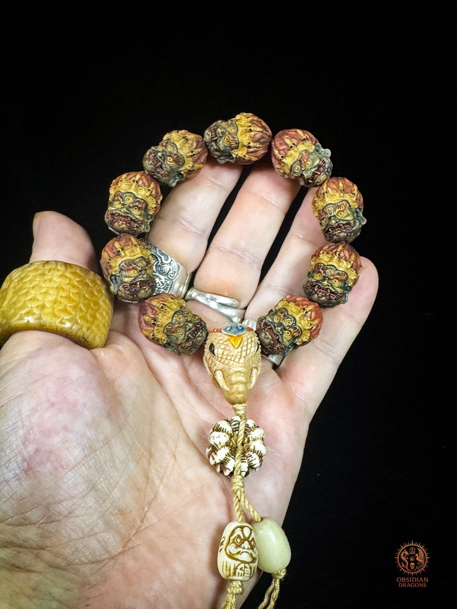 Bracelet mala Mahakala présenté dans la main pour montrer son échelle, avec neuf perles, Guru Ganesh Kangiten et Daruma