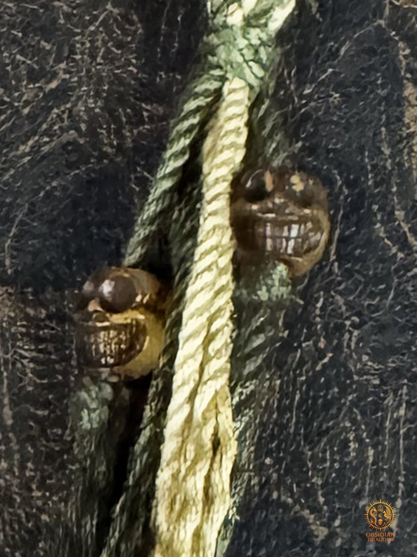 Gros plan sur les deux petits crânes en bois de cerf suspendus au tassel du bracelet bouddhiste Mahakala