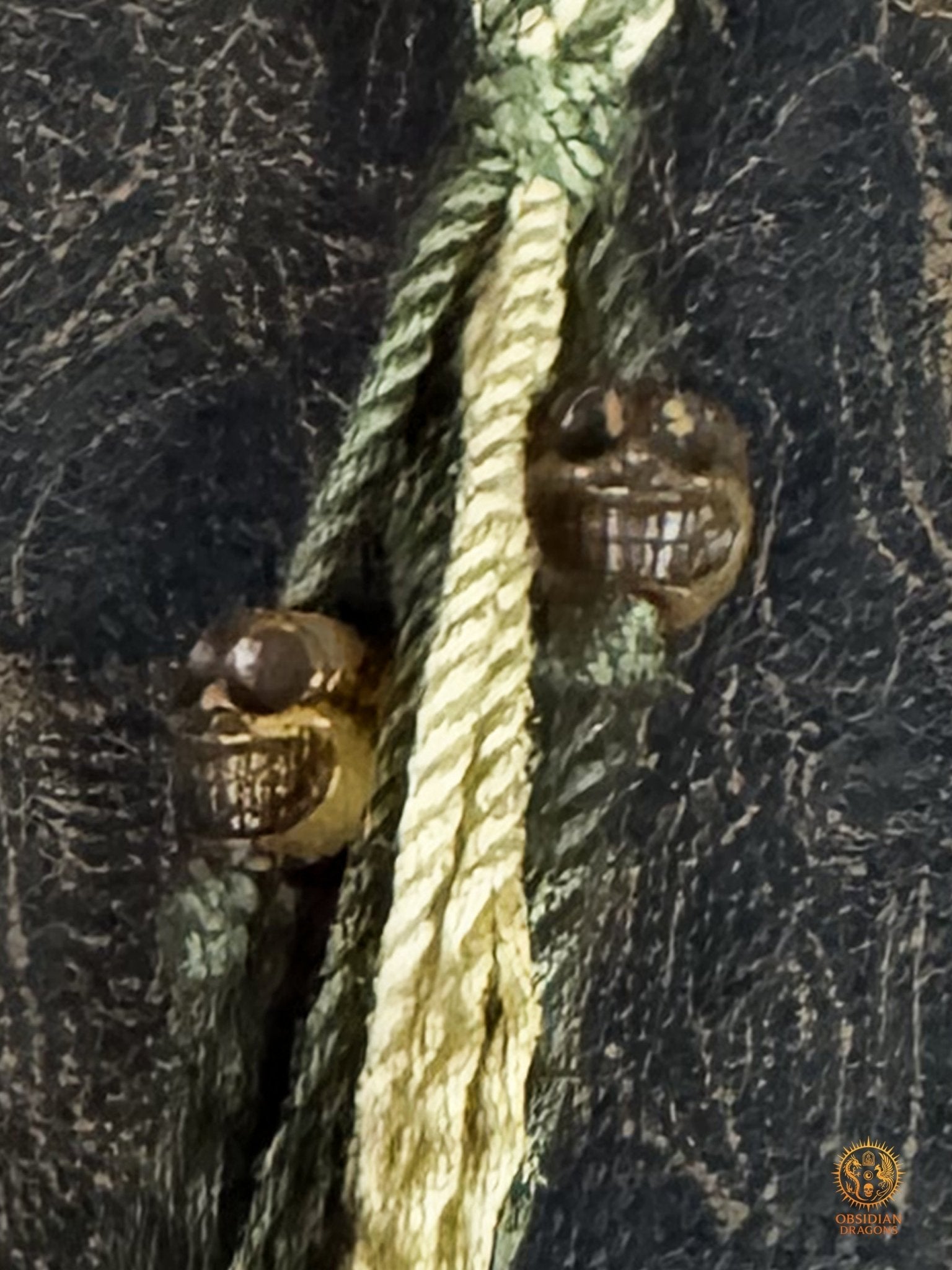 Gros plan sur les deux petits crânes en bois de cerf suspendus au tassel du bracelet bouddhiste Mahakala