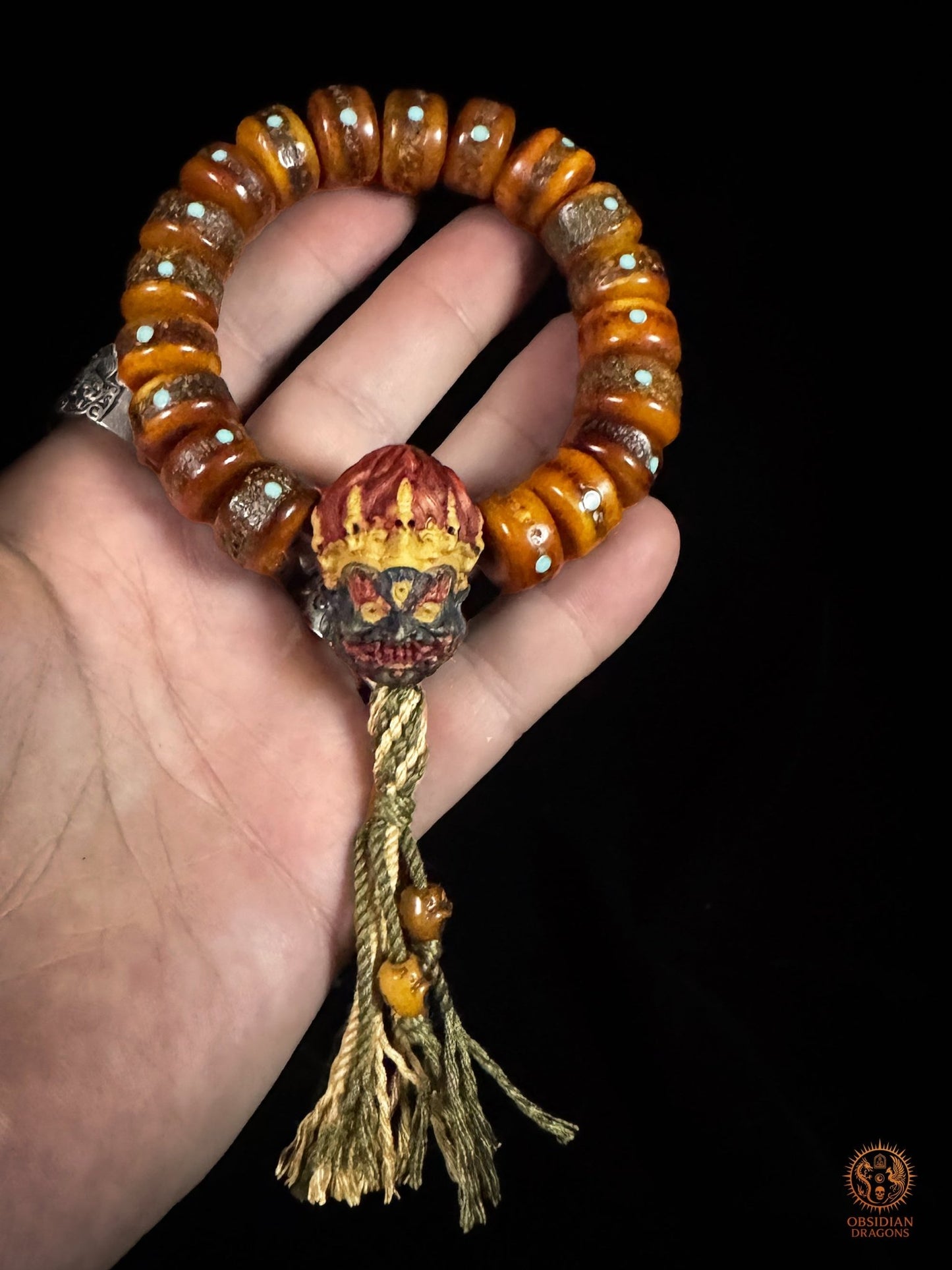 Bracelet Mahakala présenté dans une main pour montrer son volume, ses perles en os de buffle, turquoises et tassel