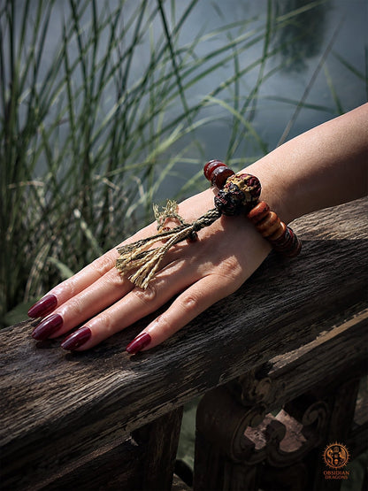 Bracelet Mahakala porté sur un poignet féminin près d’un lac, tête en bois de cerf, os de buffle et tassel artisanal