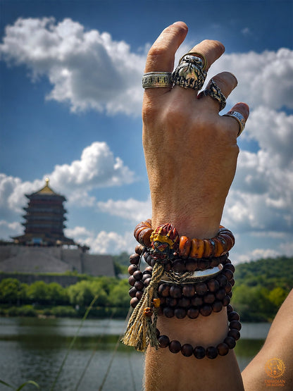 Bracelet bouddhiste Mahakala porté avec des malas devant un lac et une pagode sous le ciel bleu de Wudangshan