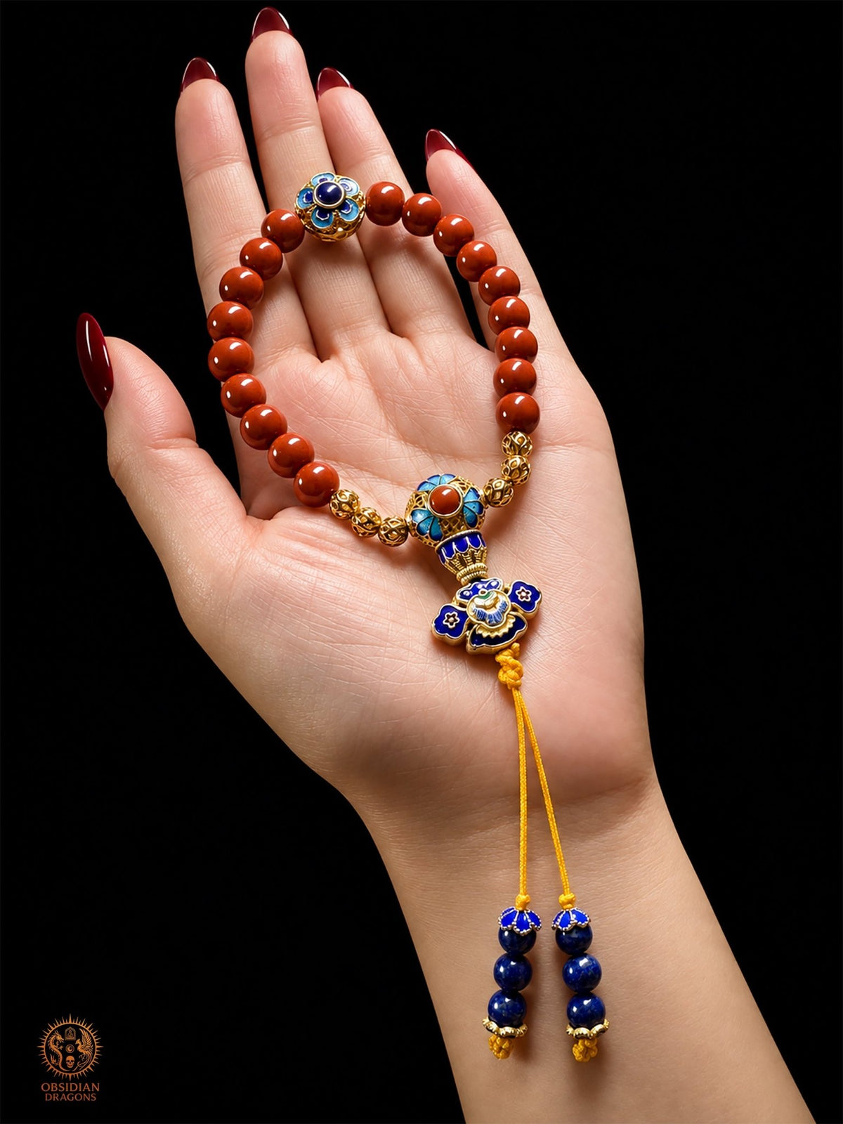 Bracelet mala Shibazi 18 perles en agate Nan Hong de Baoshan, cloisonné doré et lapis-lazuli, présenté dans une main - Obsidian Dragons