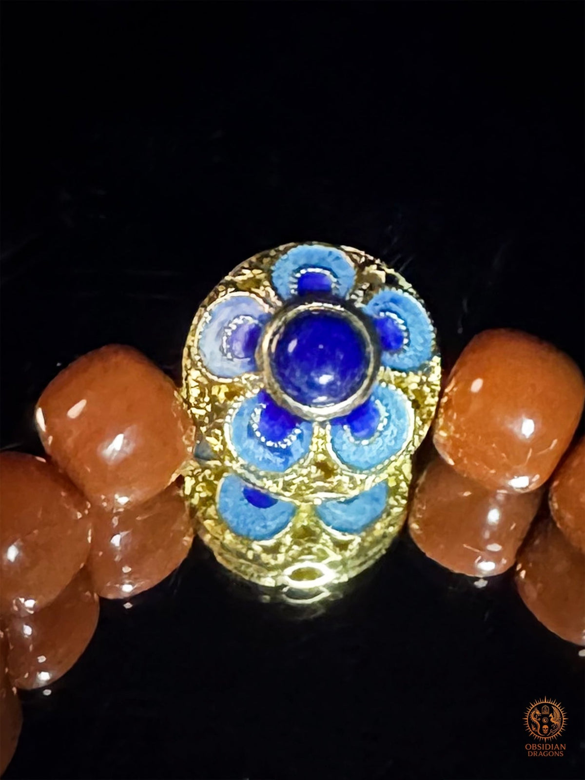 Gros plan de l’élément central floral en émail cloisonné bleu et argent plaqué or, entre les perles d’agate Nan Hong