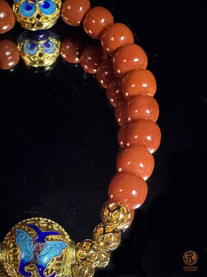 Détail des perles rouges en agate Nan Hong et de la perle Guru en cloisonné bleu et doré du bracelet mala Shibazi
