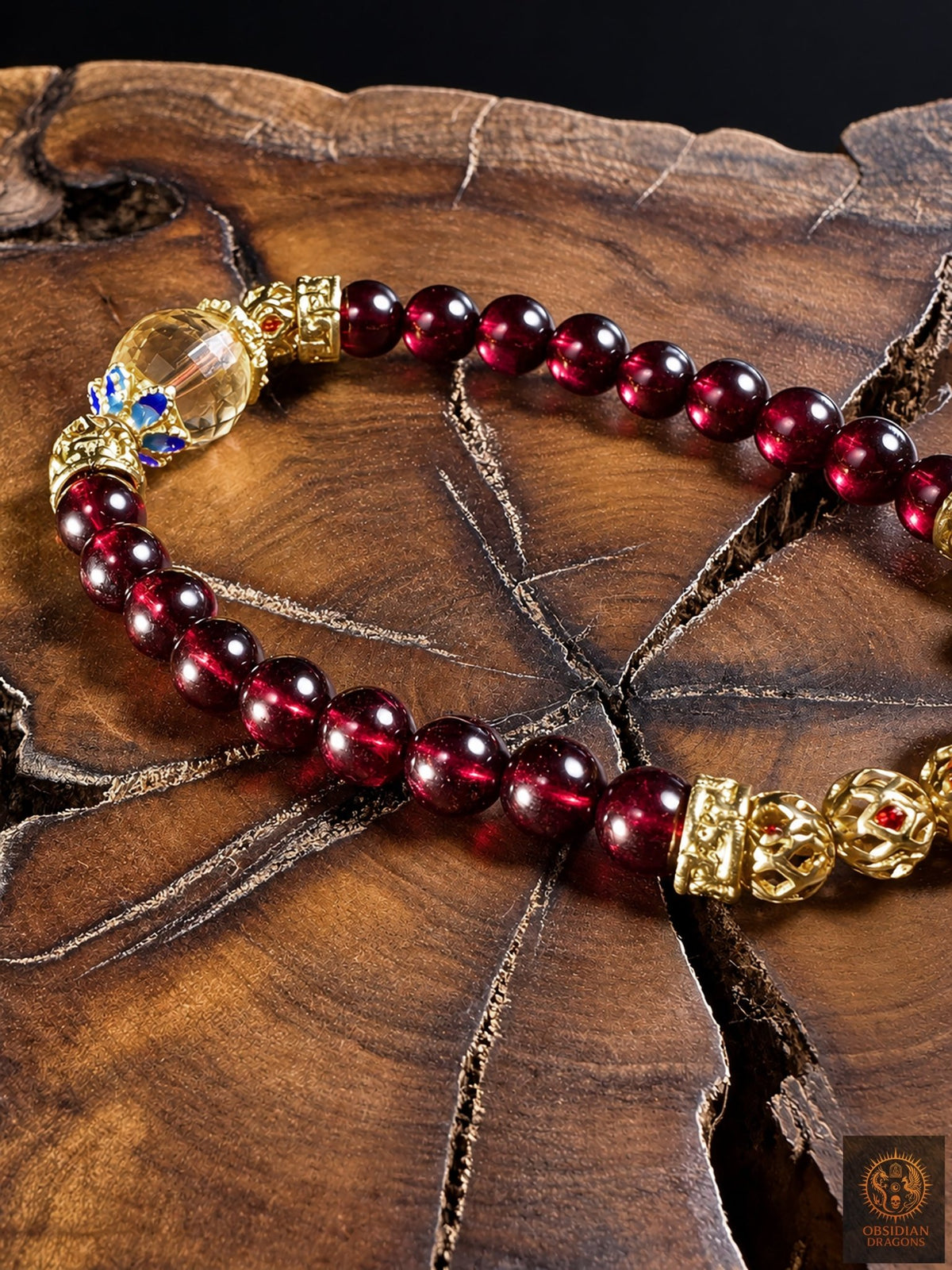Détail des perles de grenat almandin du Mozambique de 6 mm et de la citrine facettée du bracelet mala Shibazi, présenté sur bois.