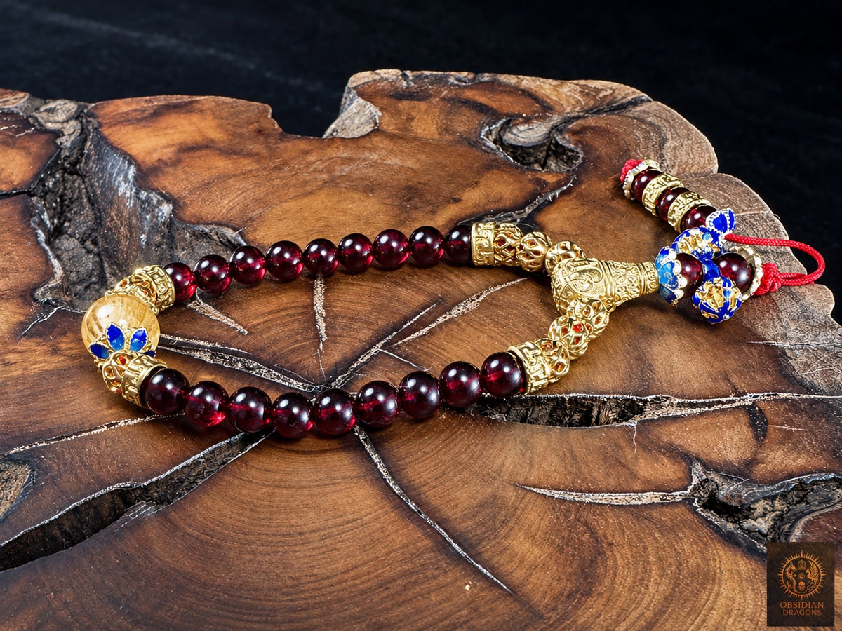 Vue oblique du bracelet mala Shibazi 18 perles en grenat et citrine, avec dorje cloisonné bleu et ornements en bronze plaqué or, sur bois.