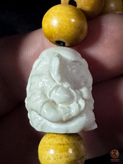 Vue latérale de Ganesh sculpté en bois de cerf sur bracelet mala à 18 perles en os de buffle patiné au thé