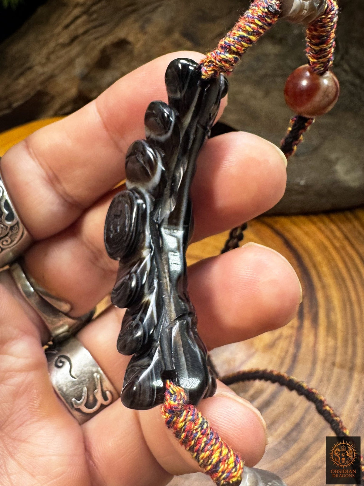 Vue de profil du pendentif Lug Mig en agate noire sculptée montrant le relief et l’épaisseur de cette pierre Œil céleste.