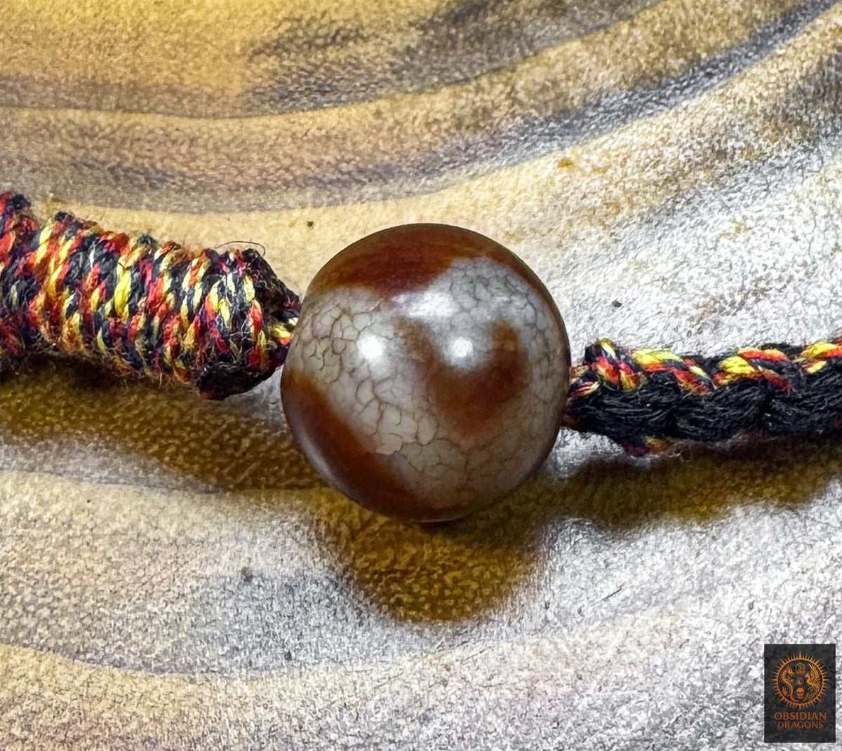 Gros plan d’une seconde perle Dzi tara en agate brune et blanche intégrée au collier Lug Mig œil magique tibétain artisanal.