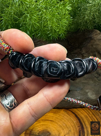 Revers du pendentif Lug Mig en agate sculptée avec motifs monétaires gravés, détail d’une amulette œil magique tibétaine.