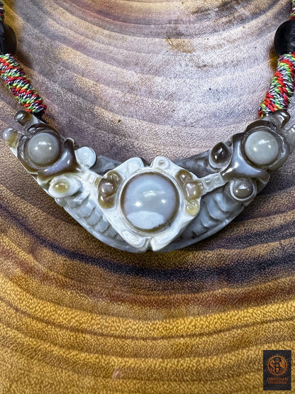 Gros plan du pendentif Lug Mig tibétain en agate oculaire naturelle, pierre Œil céleste sculptée aux motifs concentriques en forme d’yeux