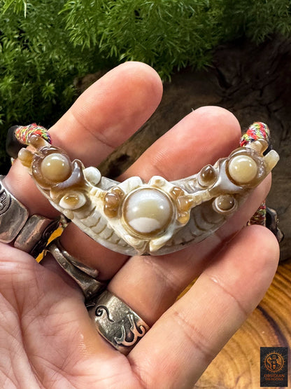 Pendentif Lug Mig traditionnel tenu en main, agate naturelle sculptée de Gyalthang avec grand œil central et formations orbiculaires naturelles