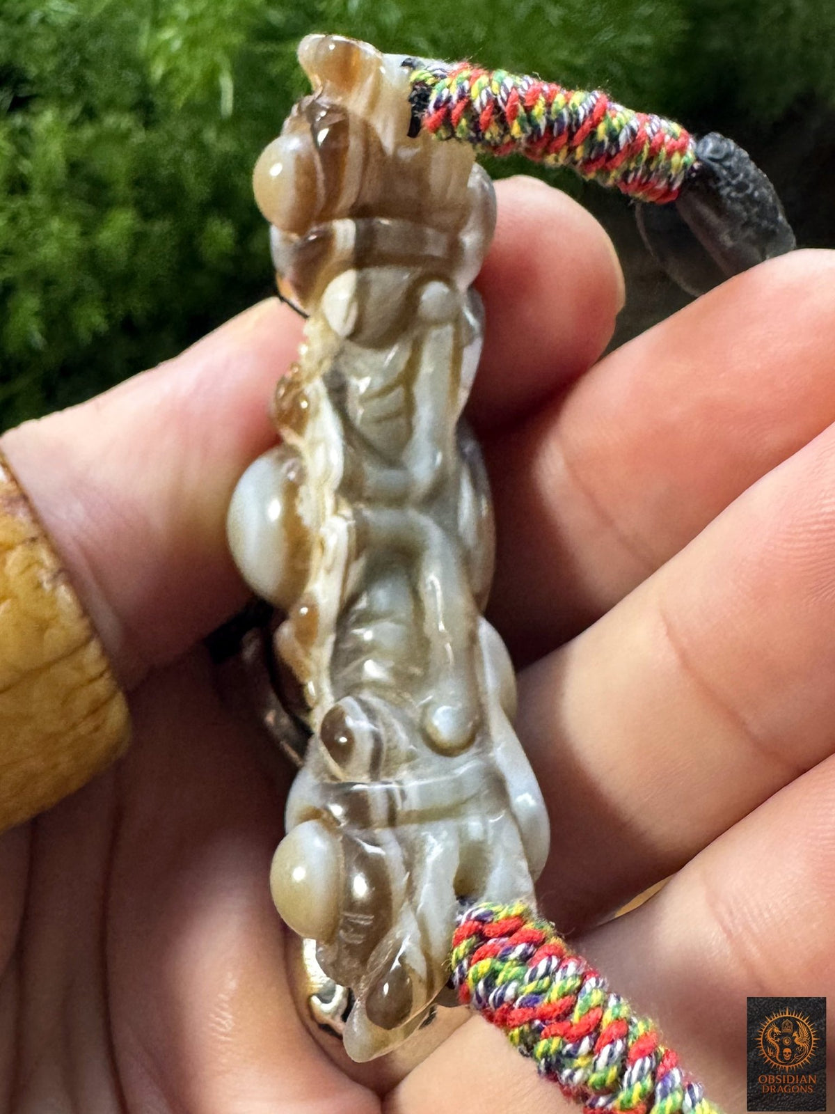 Profil opposé du Lug Mig tibétain en agate oculaire sculptée, détail du relief artisanal et du cordon multicolore tressé à la main