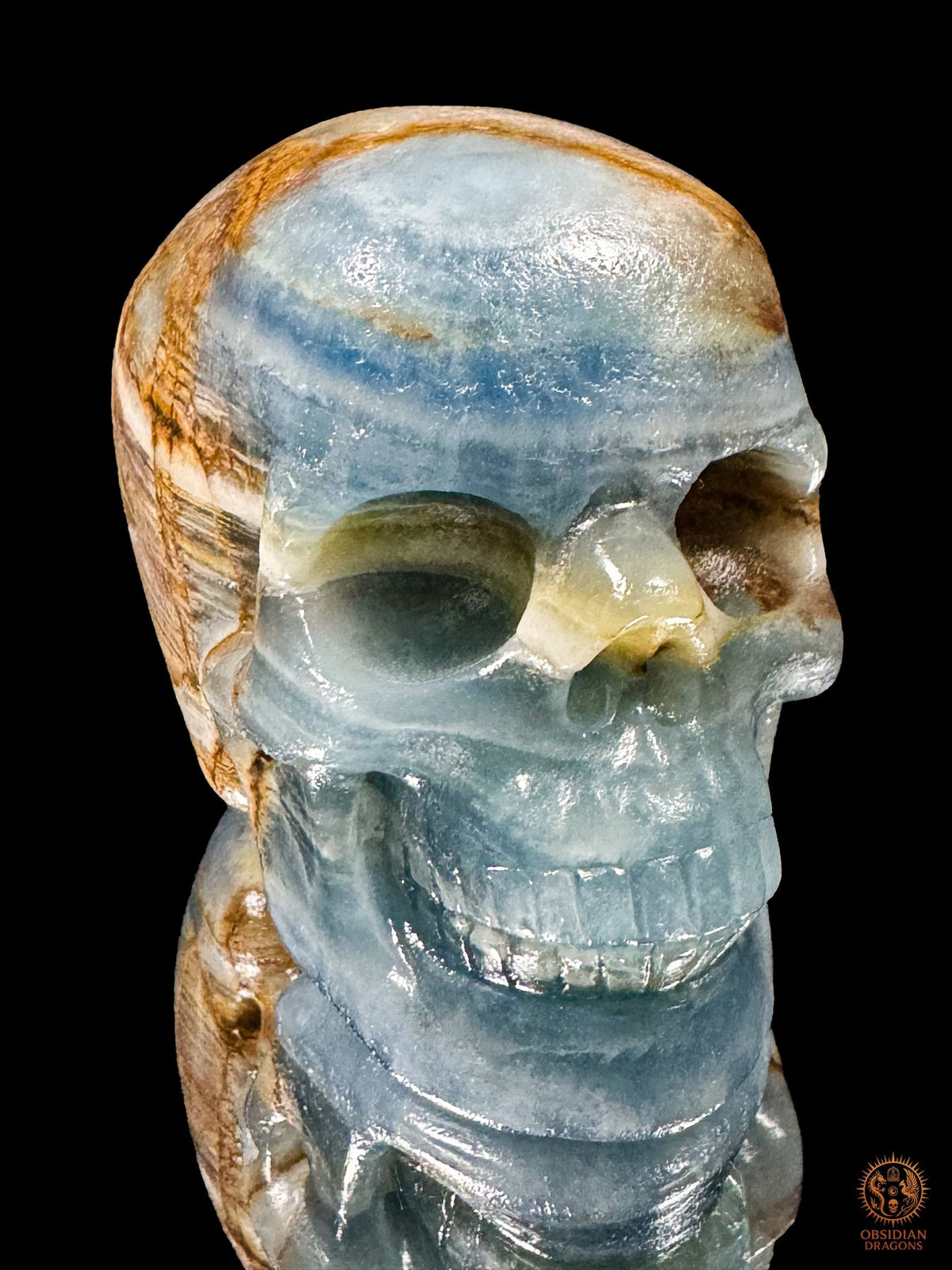 Crâne en agate bleue de Madagascar vu de trois quarts, visage tourné vers la droite, aux bandes bleues et blanches.