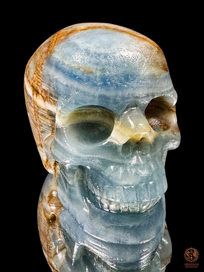 Crâne en agate bleue de Madagascar vu de trois quarts, visage tourné vers la droite, aux bandes bleues et blanches.