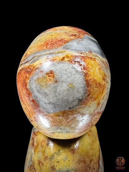 Vue arrière d’un crâne en jaspe polychrome de Madagascar, avec un grand motif gris arrondi entouré de rouge et d’ocre.