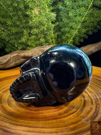 Vue du dessous rapprochée du crâne en obsidienne noire naturelle, détails du poli miroir et de la sculpture artisanale sur pierre volcanique