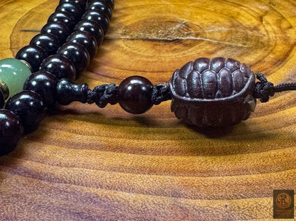Vue de profil de la carapace de tortue sculptée en santal rouge d’Inde, finition artisanale du mala bouddhiste en jade néphrite
