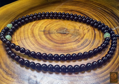 Vue générale des 108 perles de santal rouge Pterocarpus santalinus et des trois repères en jade néphrite du chapelet bouddhiste