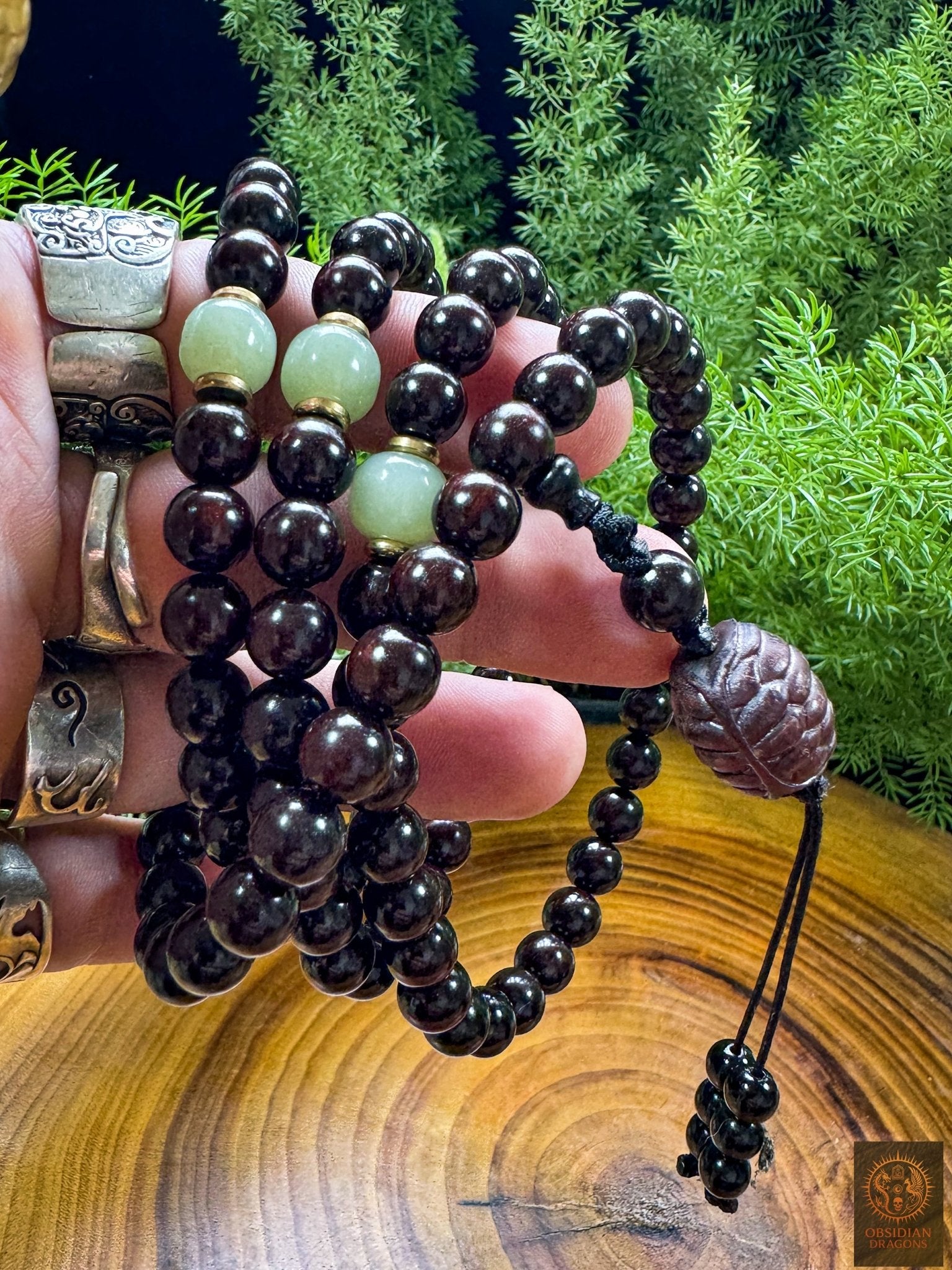 Mala bouddhiste artisanal tenu en main, composé de santal rouge, jade Hetian, cuivre et carapace de tortue sculptée