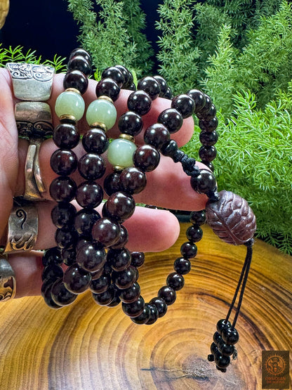 Mala bouddhiste artisanal tenu en main, composé de santal rouge, jade Hetian, cuivre et carapace de tortue sculptée