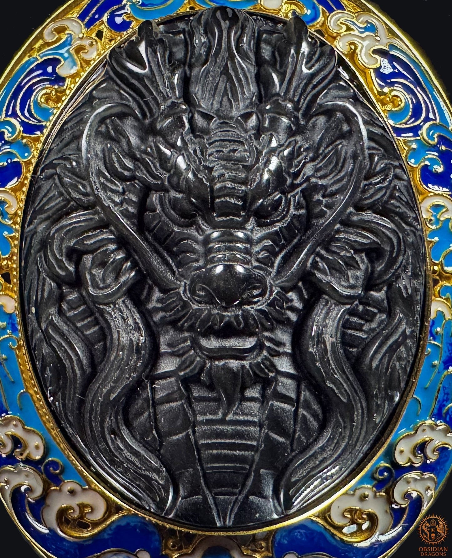 Gros plan du dragon sculpté dans l’obsidienne œil céleste, entouré de vagues bleues en vermeil et émail cloisonné