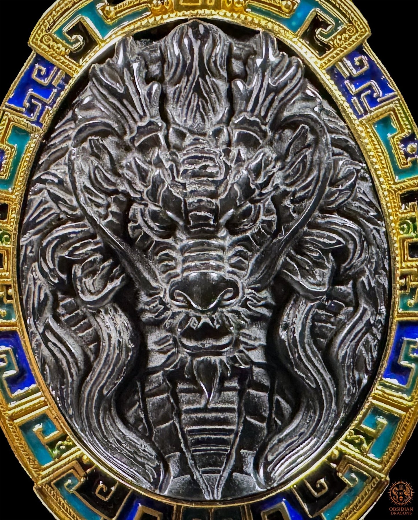 Gros plan du dragon sculpté dans l’obsidienne œil céleste, entouré de vermeil et d’émail cloisonné bleu et turquoise