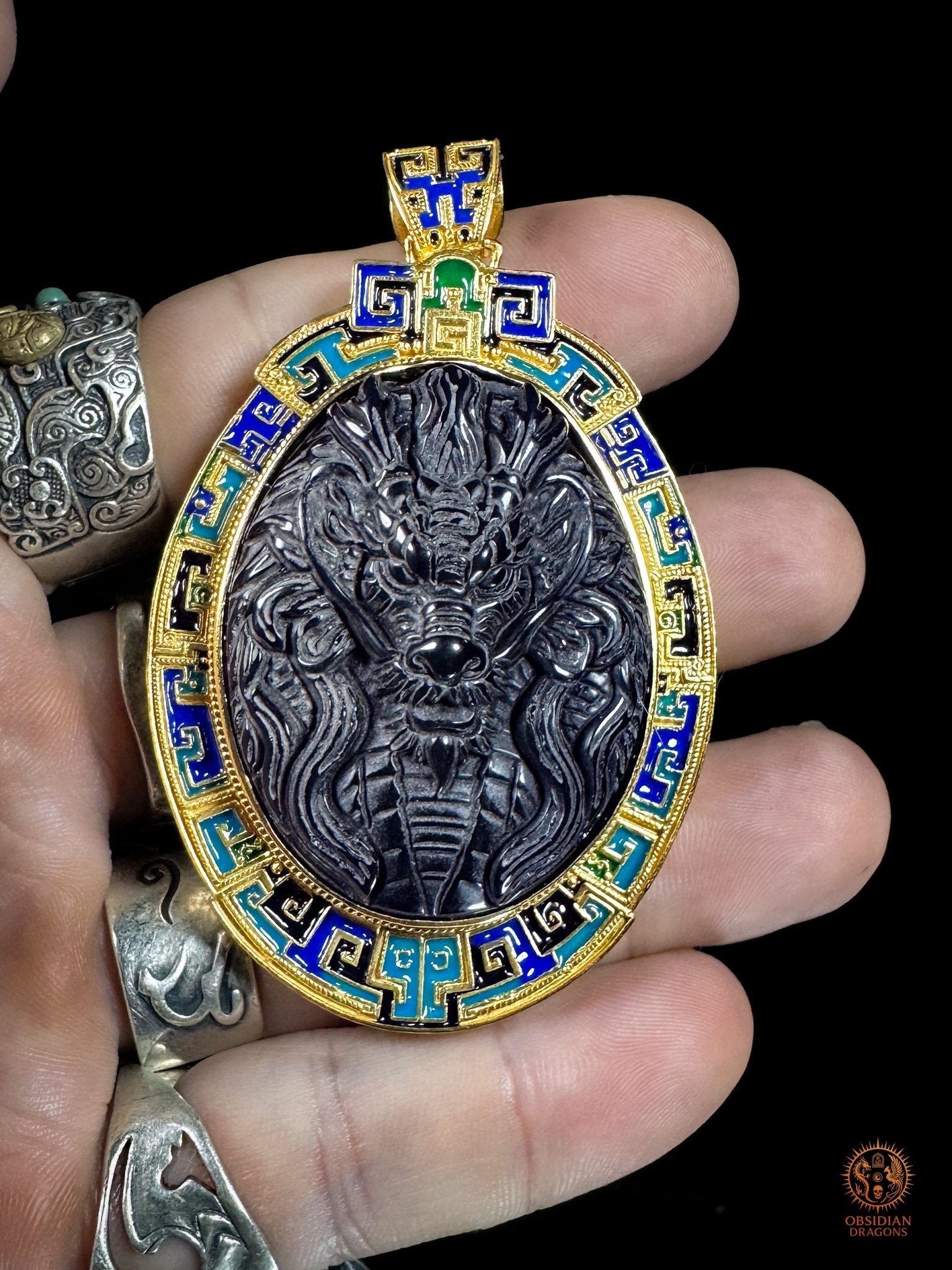 Pendentif Dragon du Tonnerre tenu en main pour montrer ses dimensions, avec obsidienne sculptée, vermeil et émail cloisonné
