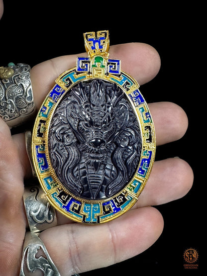 Pendentif Dragon du Tonnerre tenu en main pour montrer ses dimensions, avec obsidienne sculptée, vermeil et émail cloisonné