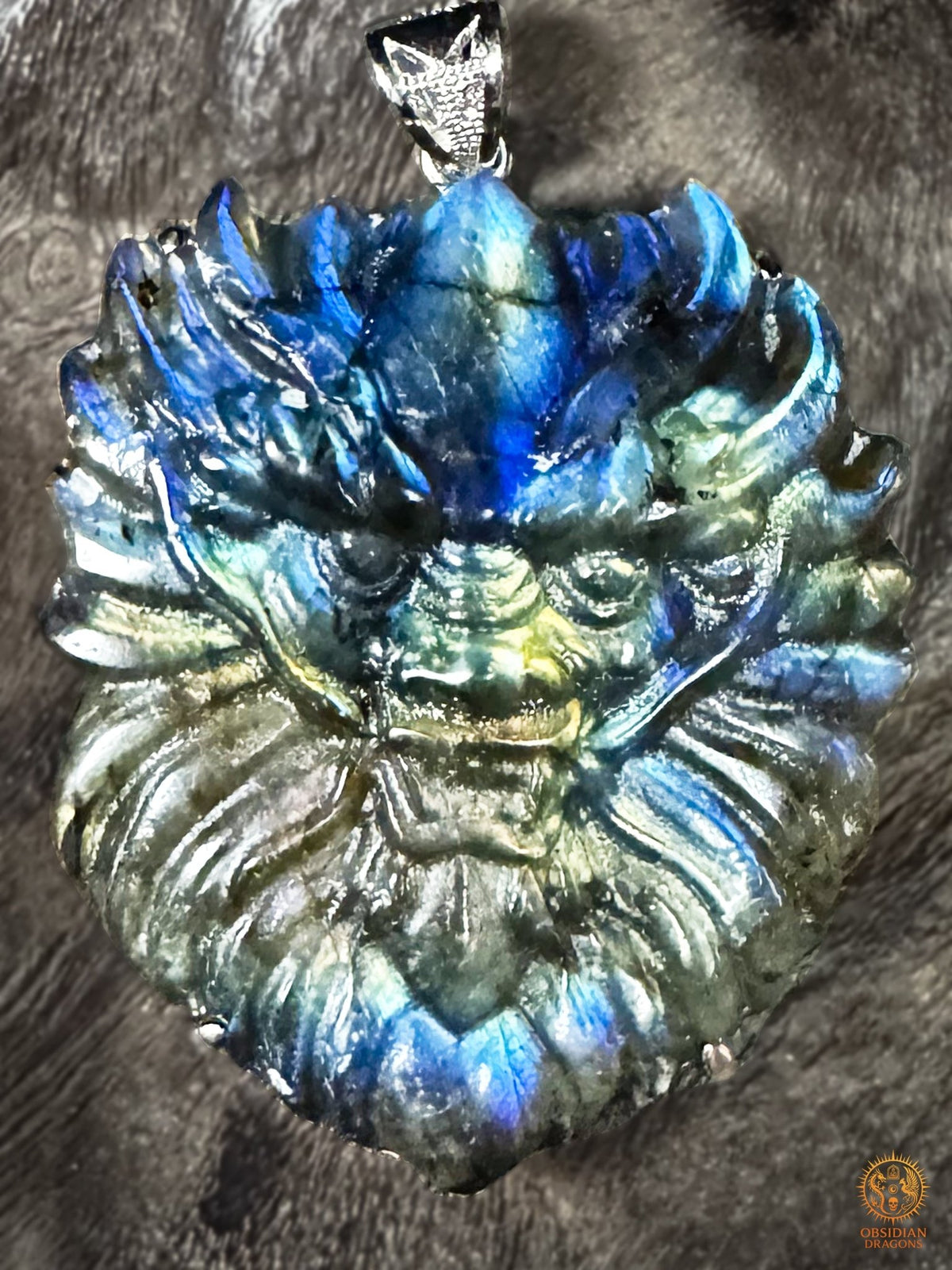 Gros plan sur la tête de dragon sculptée en labradorite naturelle, aux reflets bleus, verts et dorés, avec bélière en argent 925