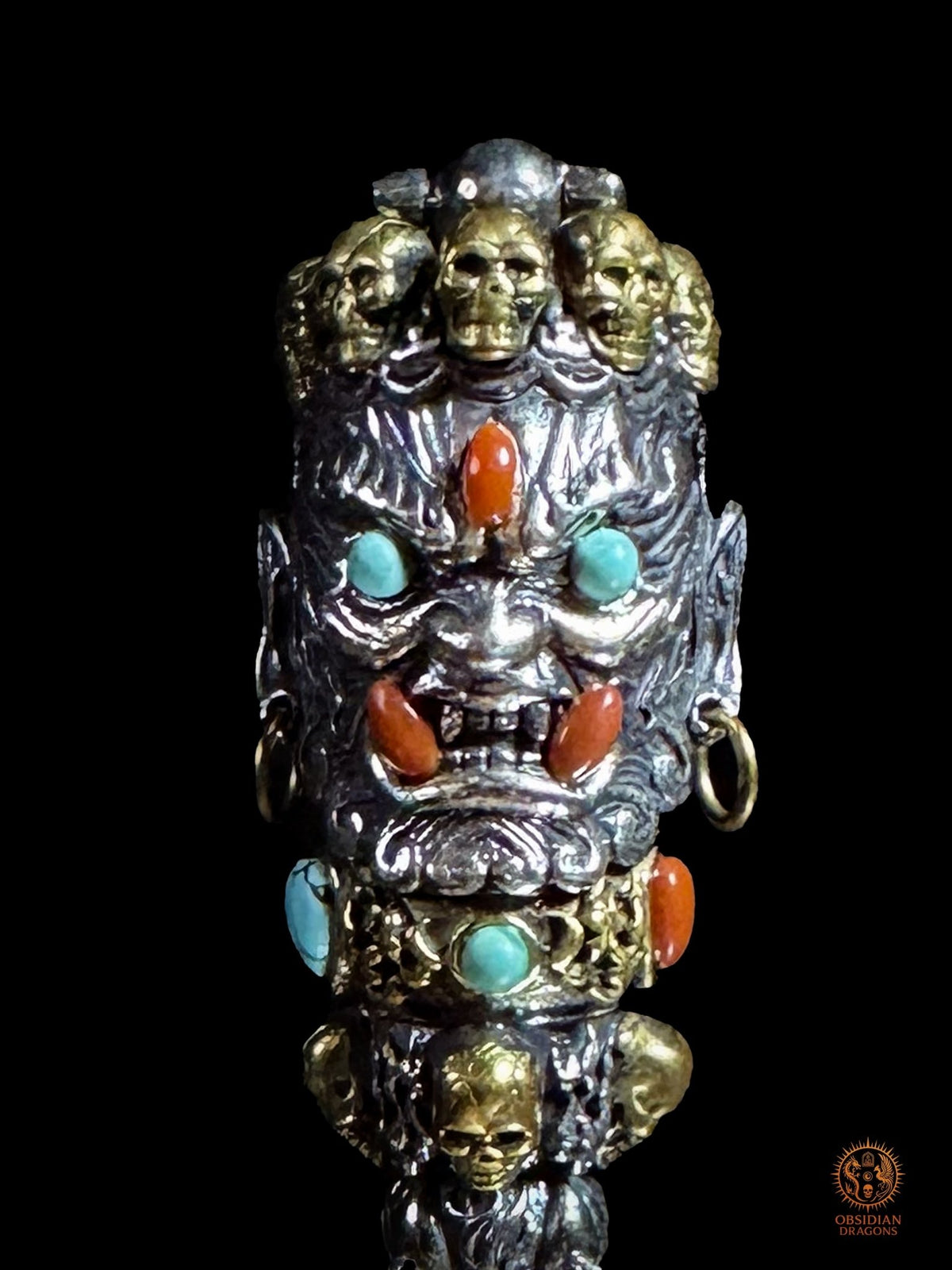 Détail du visage courroucé de Mahakala sur un pendentif Phurba, yeux en turquoise naturelle, cabochons rouges Nan Hong, argent 925 et bronze