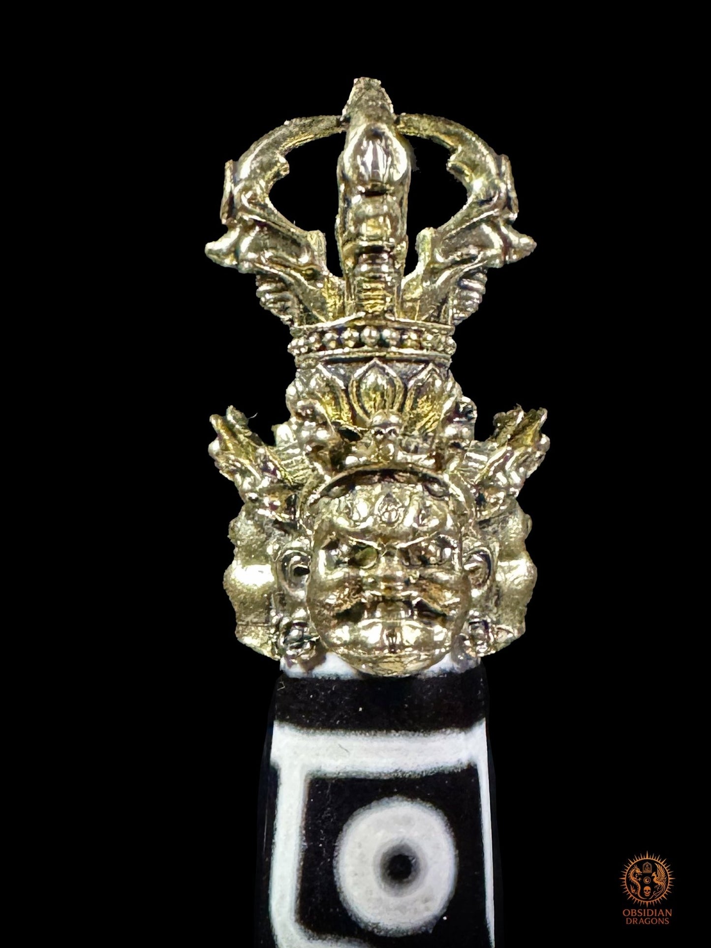 Détail de la poignée du Phurba avec DZI à 9 yeux avec visages courroucés et vajra au-dessus du DZI

