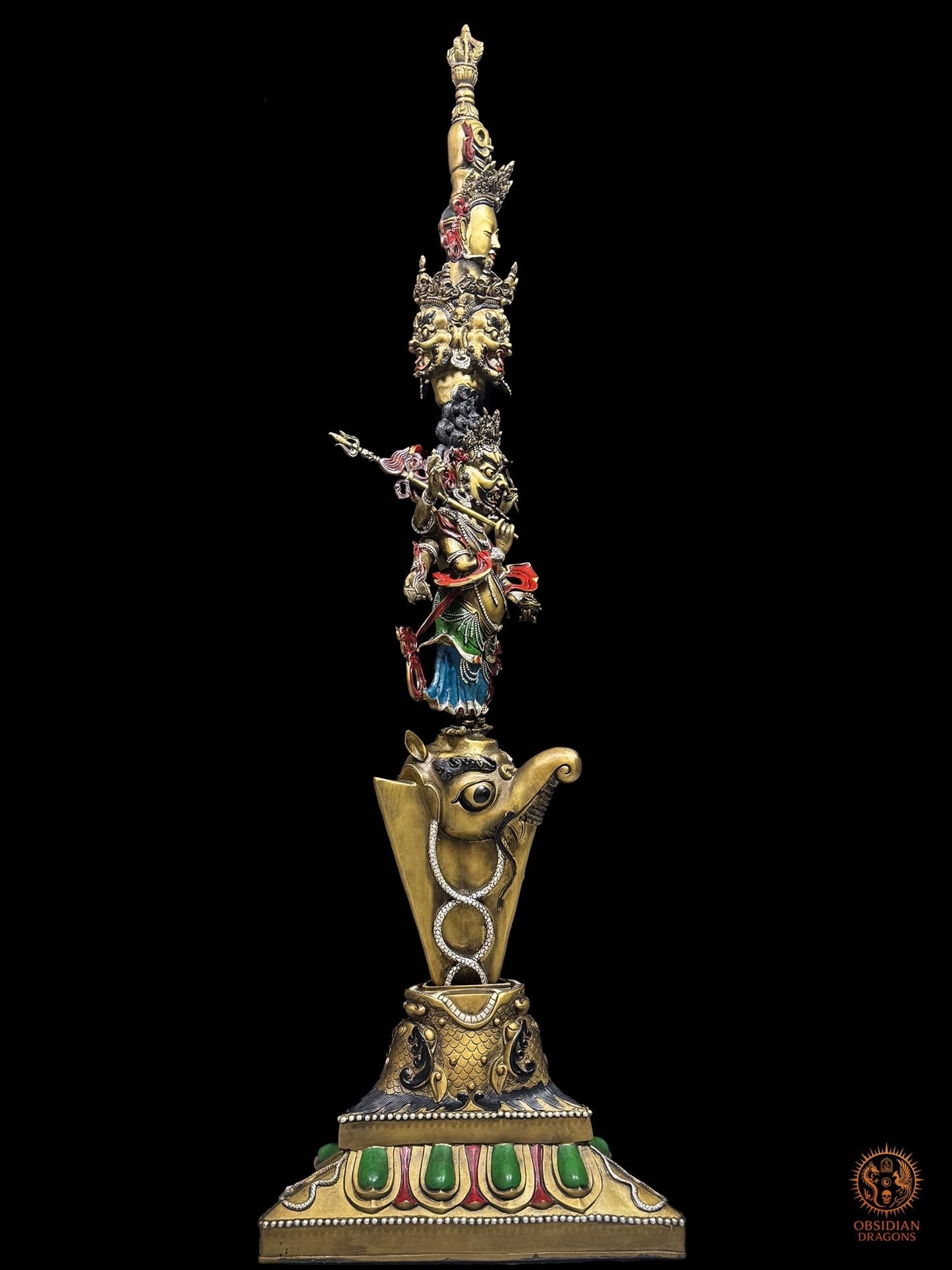 Vue de profil du phurba tibétain monumental en bronze, montrant la profondeur de la sculpture, le makara et les divinités vajrayana