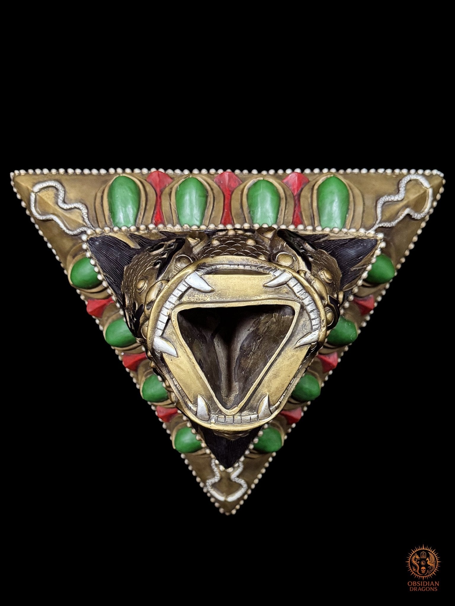 Vue plongeante du socle triangulaire du phurba tibétain, gueule monstrueuse ouverte recevant la lame rituelle à trois faces