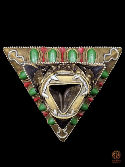 Vue plongeante du socle triangulaire du phurba tibétain, gueule monstrueuse ouverte recevant la lame rituelle à trois faces