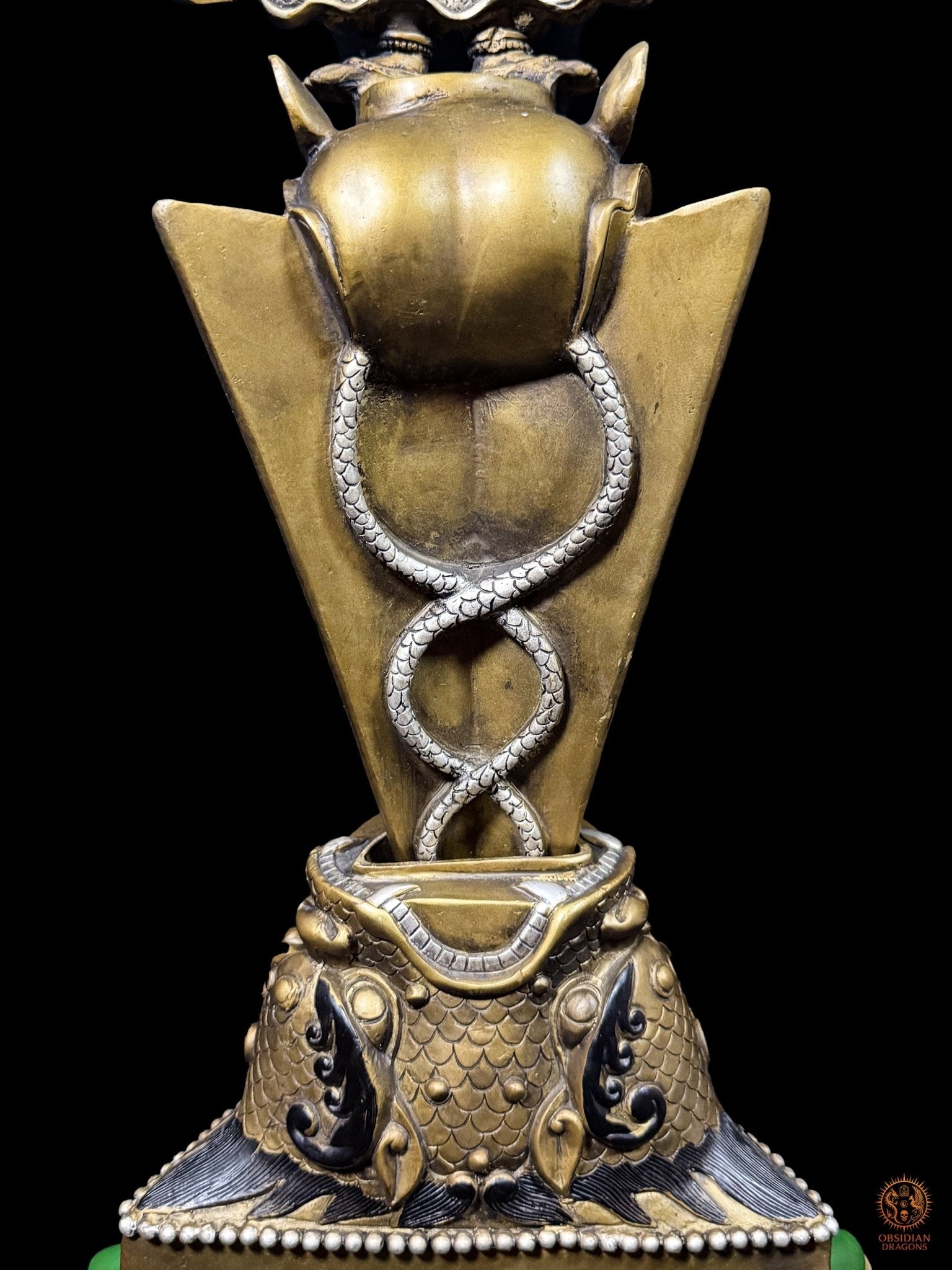 Vue arrière de la lame triangulaire du phurba tibétain avec nāga entrelacés et socle rituel en bronze, art bouddhiste vajrayana