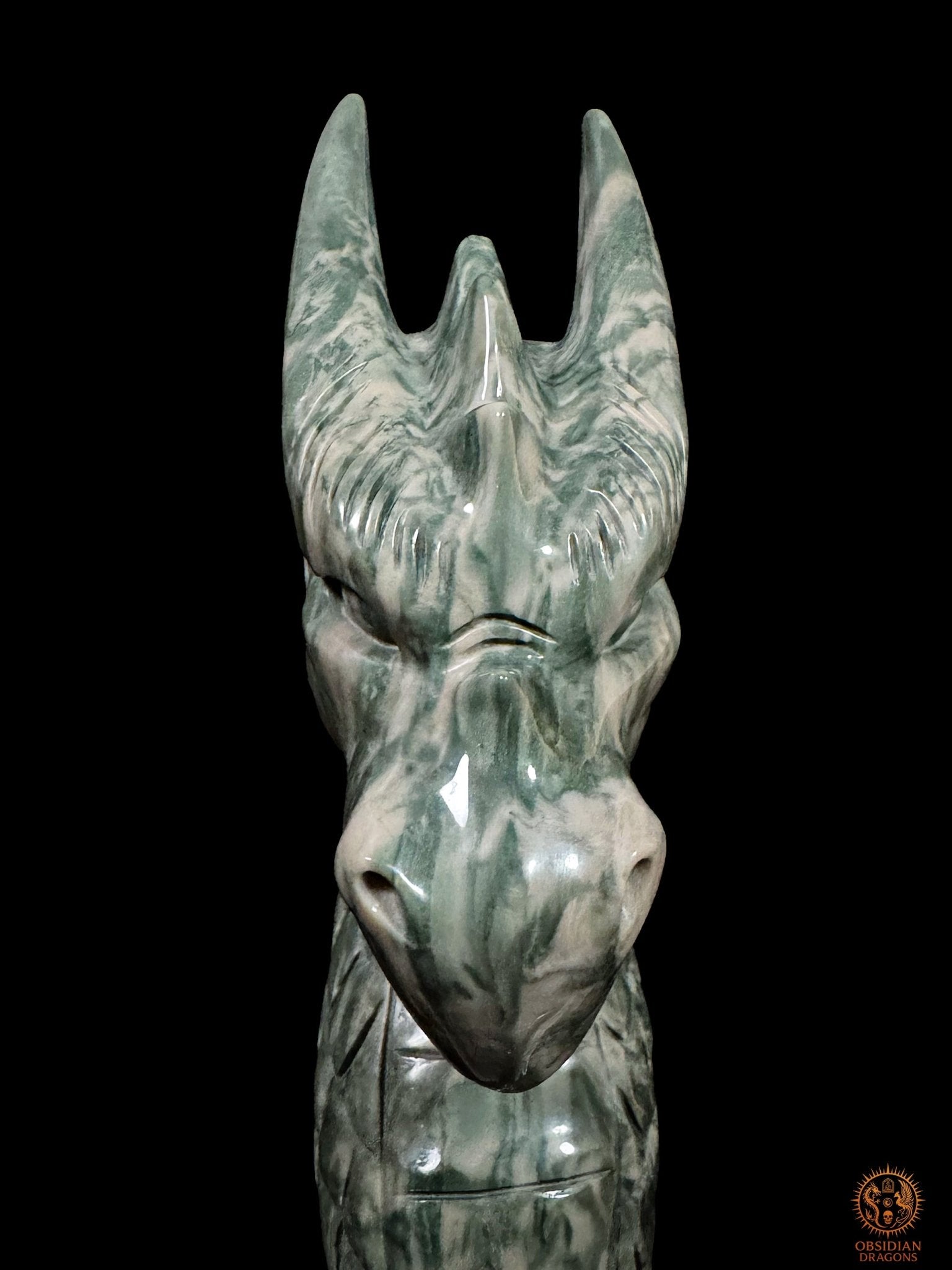 Portrait frontal rapproché du dragon gardien en jade culturel chinois, montrant son regard sculpté, son museau poli et ses longues cornes