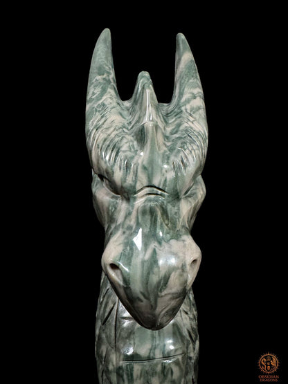Portrait frontal rapproché du dragon gardien en jade culturel chinois, montrant son regard sculpté, son museau poli et ses longues cornes