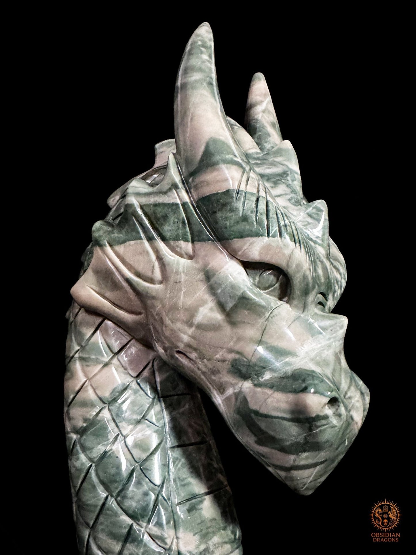 Gros plan sur la tête de dragon en jade Jiulong, ses longues cornes et les veinures vertes et crème du Hua’an Yu poli
