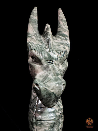 Gros plan frontal du dragon en jade des Neuf Dragons, révélant son regard sculpté, son museau fermé et ses cornes rubanées
