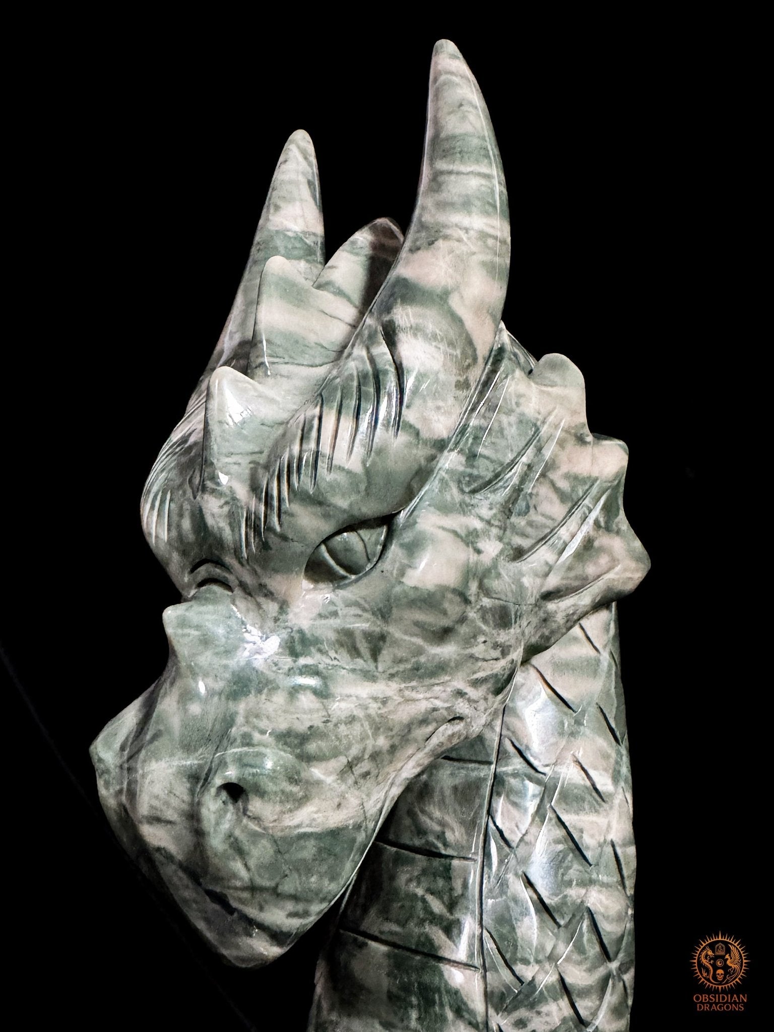Détail du visage du dragon en jade Jiulong, avec œil profondément sculpté, cornes dressées et motifs de pierre-paysage
