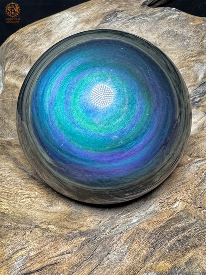 Sphère en obsidienne Manta Huichol du Mexique de 6,37 cm, aux couronnes bleu turquoise et violettes, posée sur bois - Obsidian Dragons