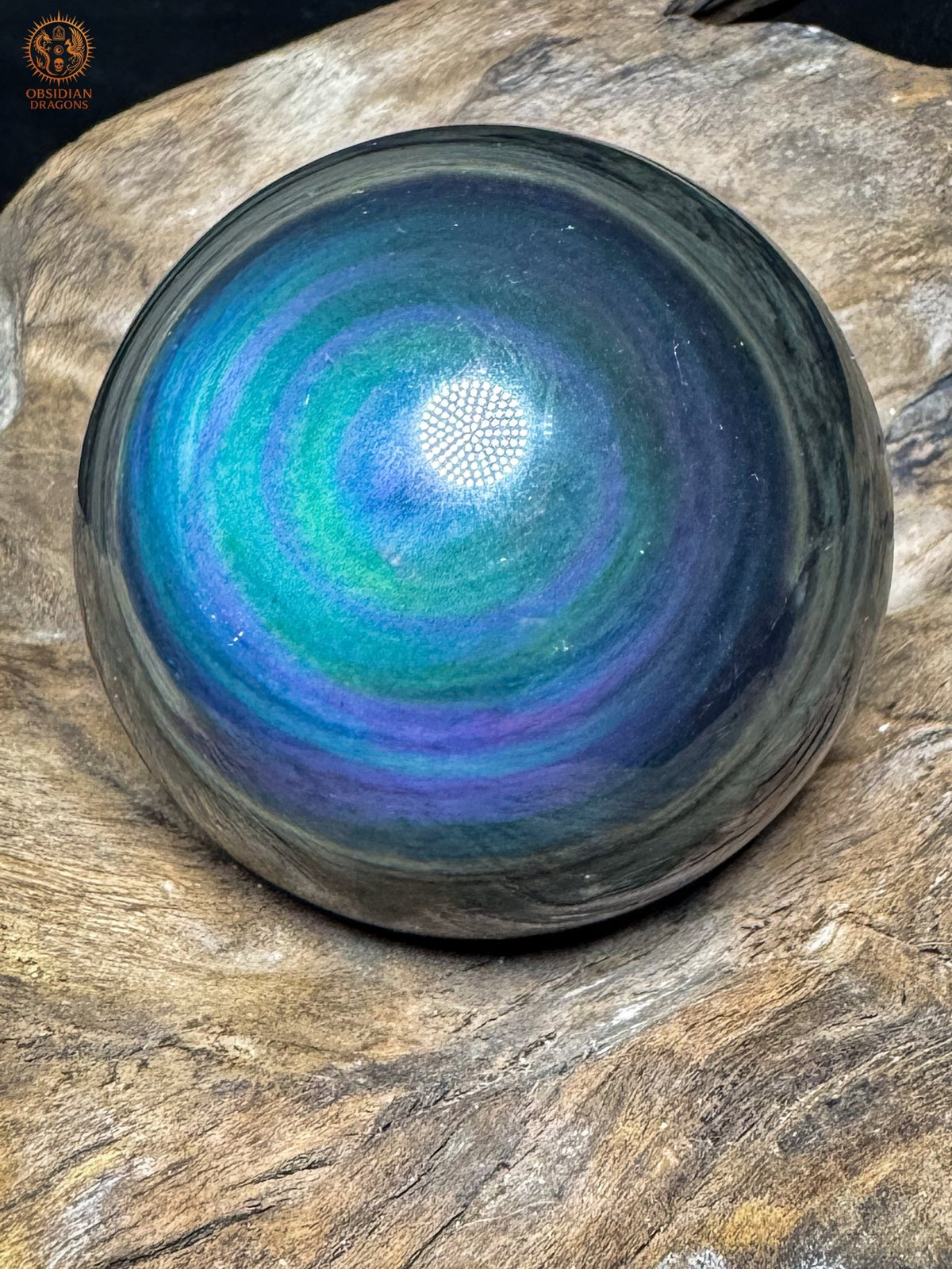 Obsidienne œil céleste Manta Huichol vue de biais, anneaux bleu turquoise et violets entourés de bandes sombres.