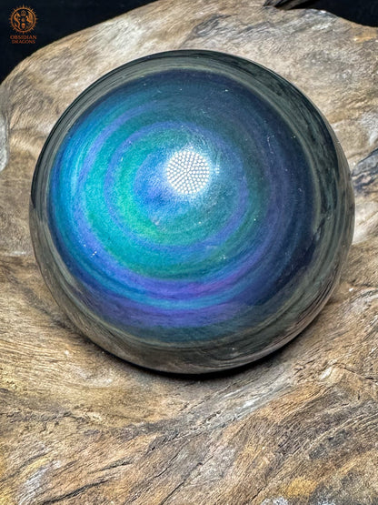 Obsidienne œil céleste Manta Huichol vue de biais, anneaux bleu turquoise et violets entourés de bandes sombres.