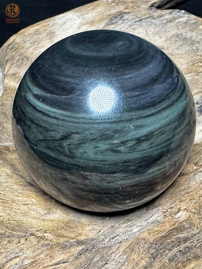 Sphère en obsidienne mentogochol sous un angle sombre, bandes gris-vert et gris-violet aux contours irréguliers.