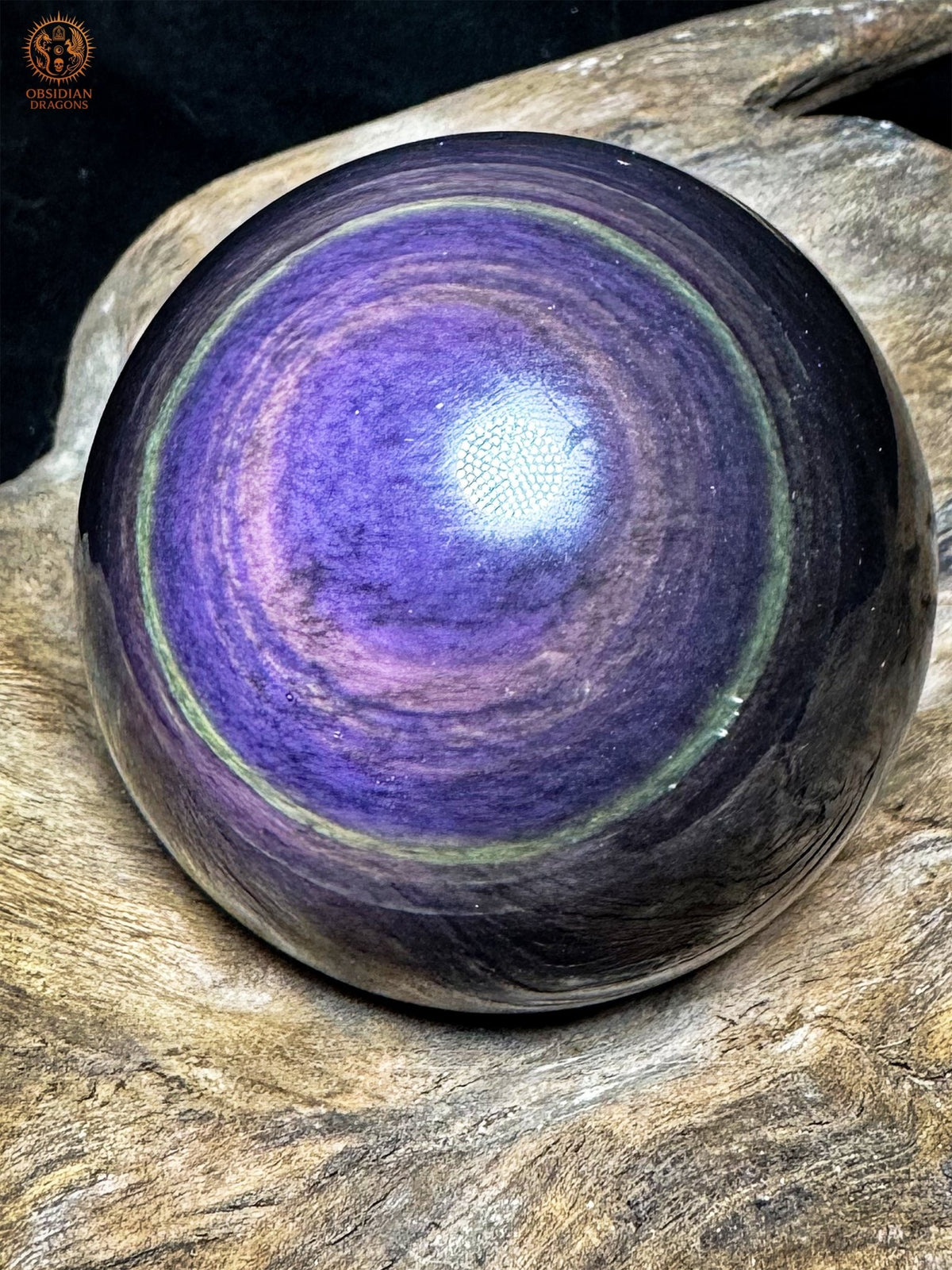 Vue rapprochée de la sphère en obsidienne œil céleste, dessin bleu-violet panaché entouré de bandes rosées et d’une bordure verte.